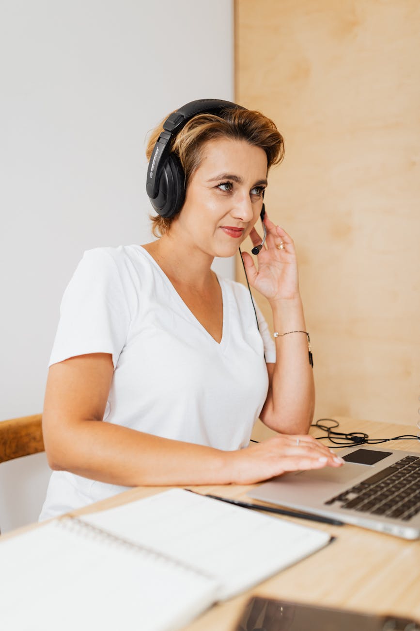 woman sitting at the desk wearing a headset and using a laptop