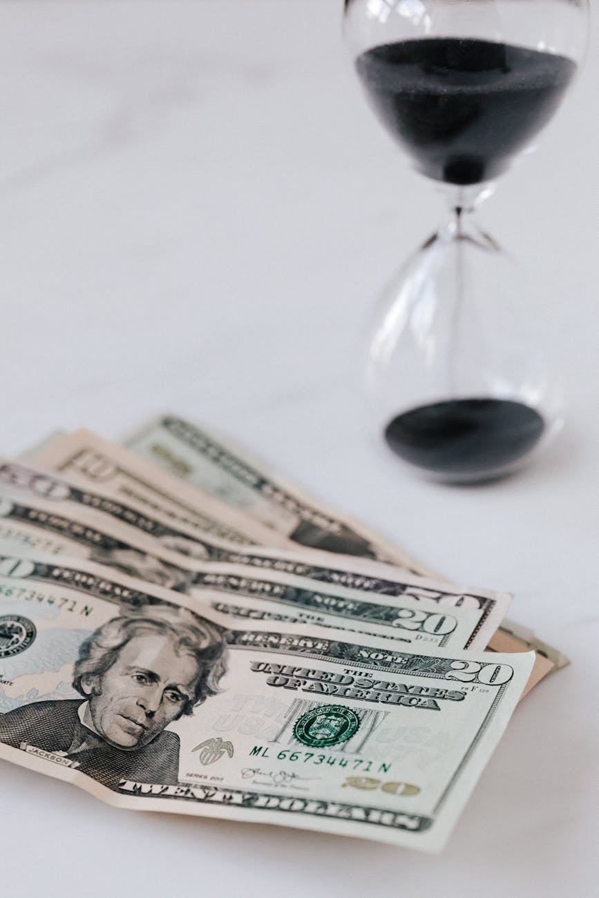 heap of banknotes beside hourglass